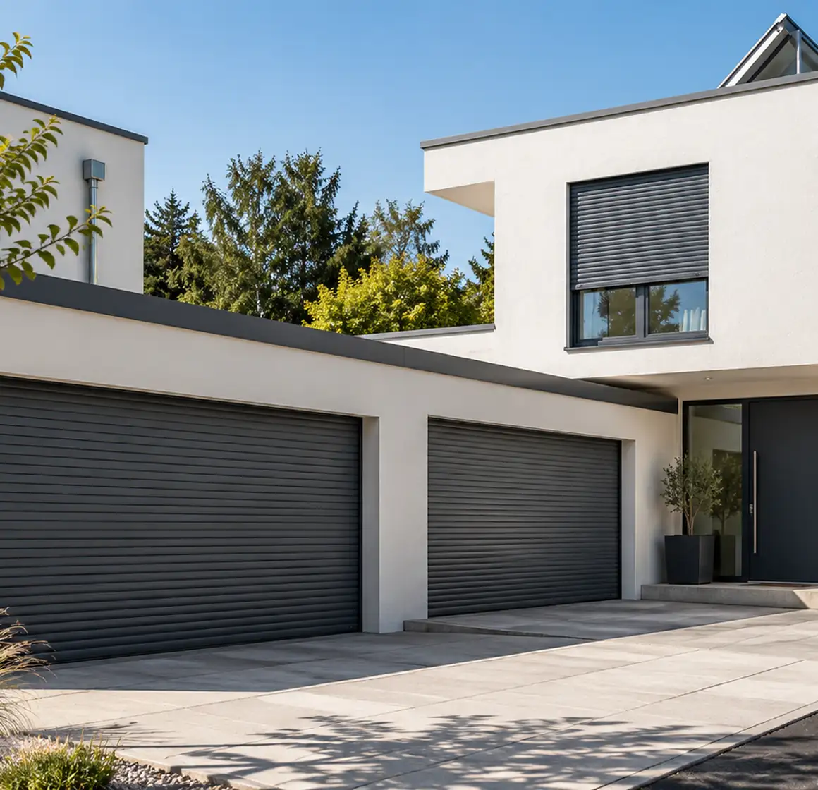 Moderne Doppelgarage mit anthrazitfarbenen Rolltoren neben dem Hauseingang